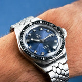 Yema Superman Steel Blue CMM.10 indossato al polso, quadrante blu acciaio con indici luminosi e ghiera nera 17.26.10.65.SN.M