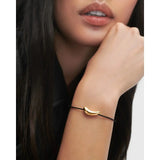 Pdpaola Bracciale Orbit Cord dettaglio ravvicinato indossato, charm dorato lucido su cordino nero PU01-937-U
