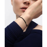 Pdpaola Bracciale Amy Diamond Cord in cordino nero con charm oro e diamanti indossato al polso, stile minimal PU05-888-U