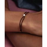 Pdpaola Bracciale Minerals Pearl Orion Cord Silver indossato al polso, dettaglio perla e cordino marrone PU02-A54-U