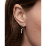 Pdpaola Orecchini Mini Twist Silver in argento rodiato dettaglio indossato su orecchio con pendente a nodo AR02-D28-U